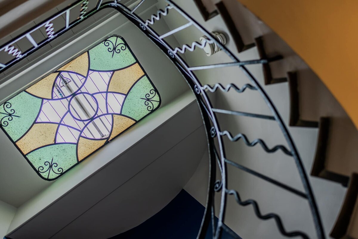 A spiral staircase with a stained glass window above it