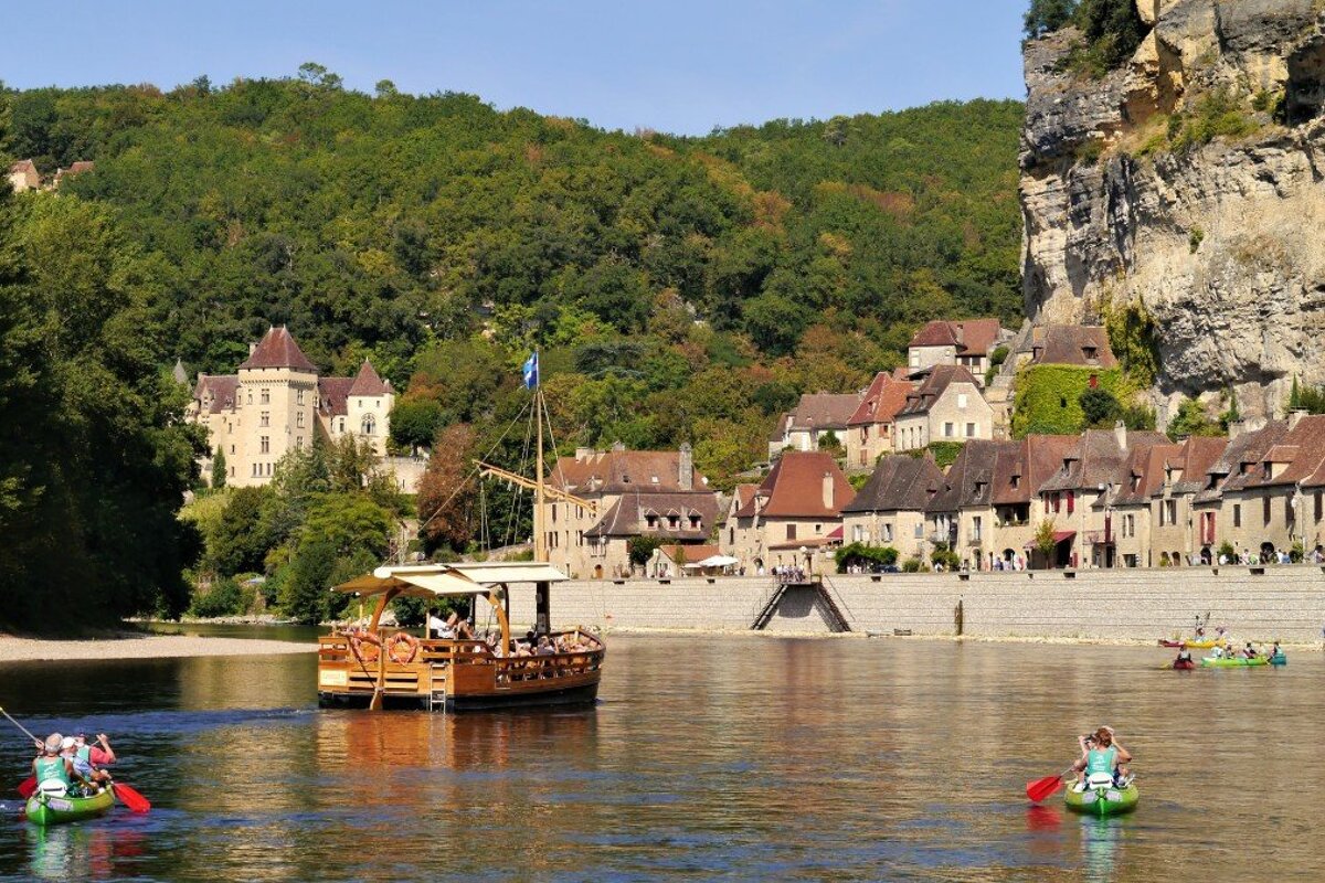 a view of canoes & a gabare on the river at la roque gageac