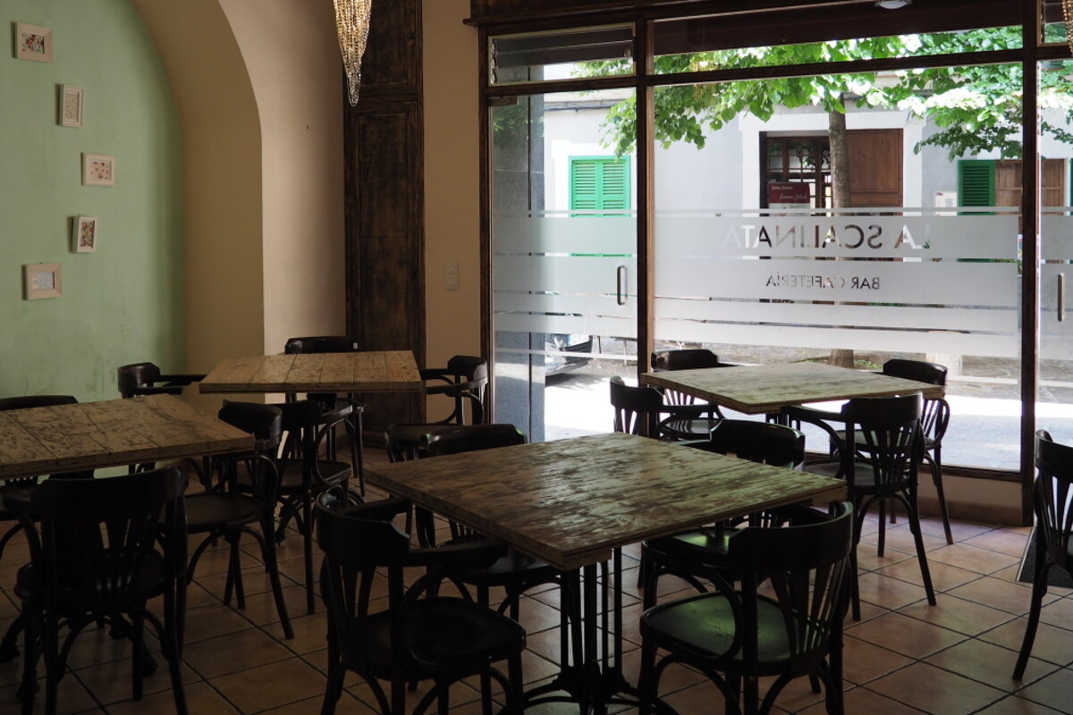 4 dining tables and wooden chairs inside a restaurant