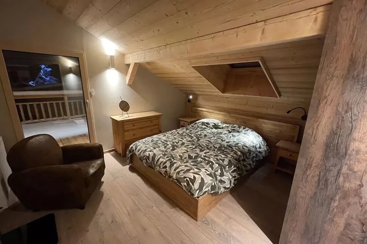 A bedroom with a large bed and a chair