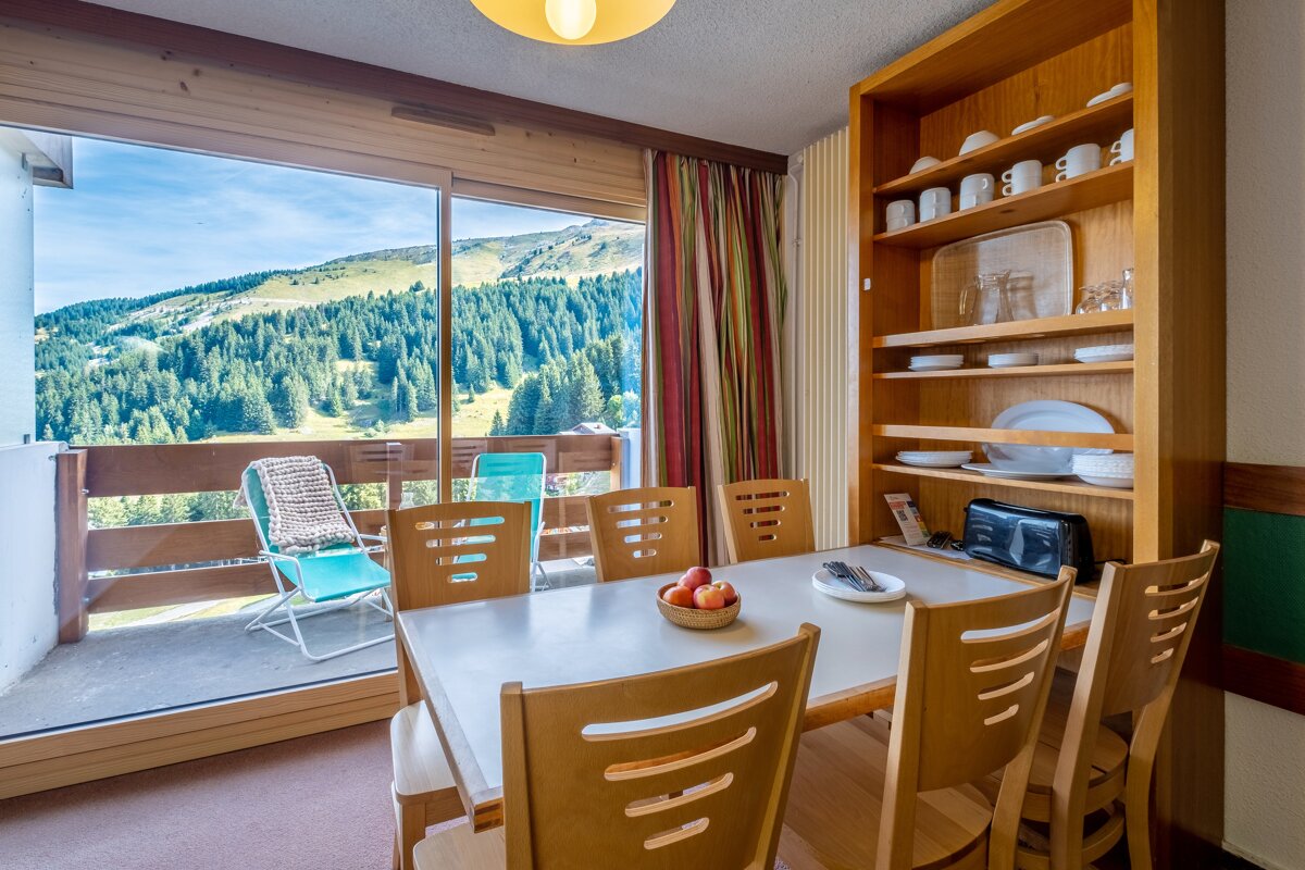 A dining room with a table and chairs and a view of the mountains