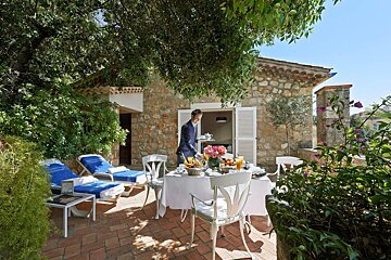 A man serving food on a patio outside of a stone building