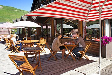 Two women sit at a table under a red and white striped umbrella