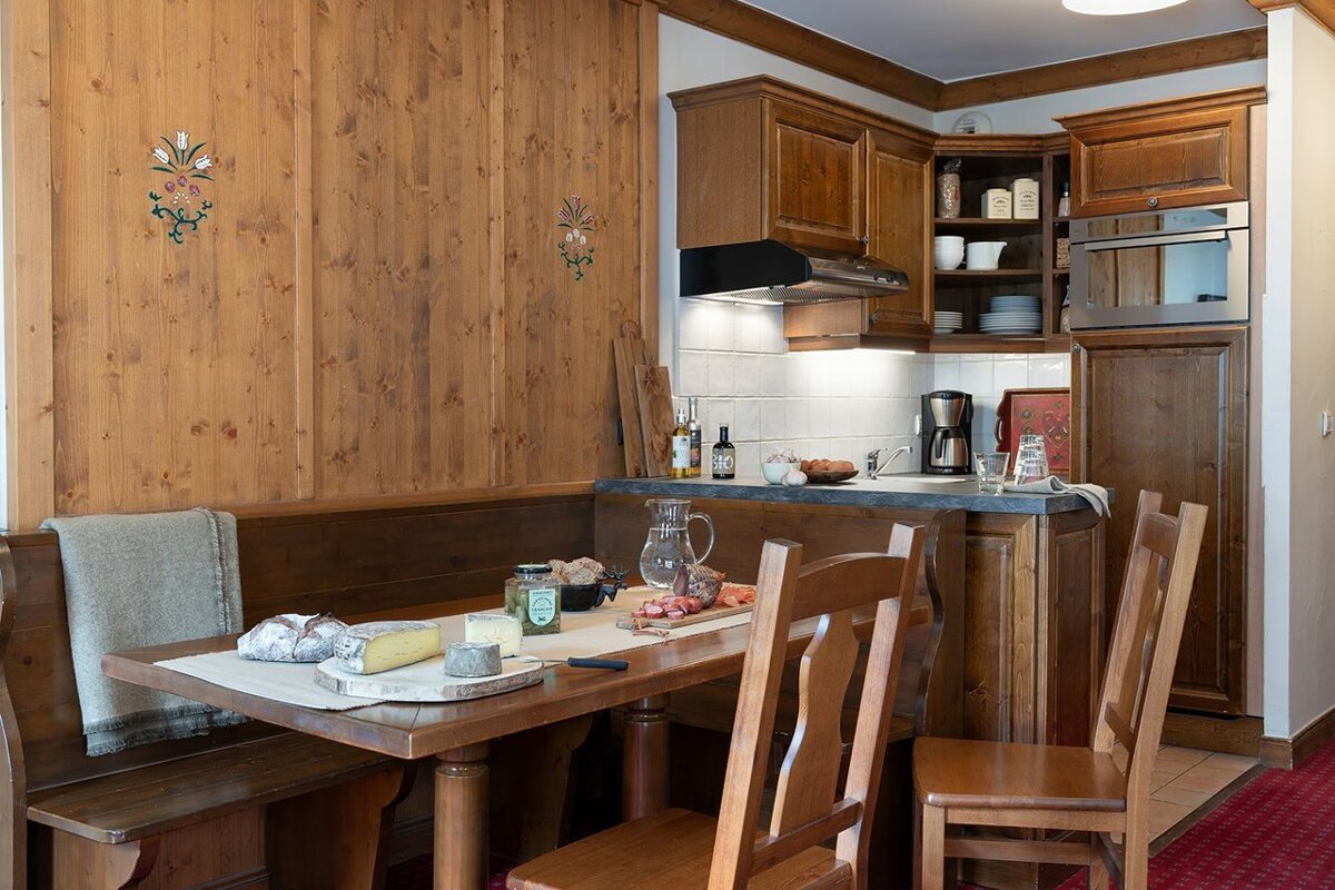 Cozy chalet-style wooden kitchen and dining area with a table set with cheese, bread, and cold cuts.