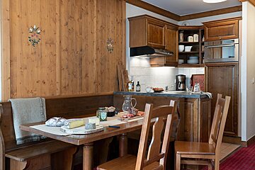 Cozy chalet-style wooden kitchen and dining area with a table set with cheese, bread, and cold cuts.