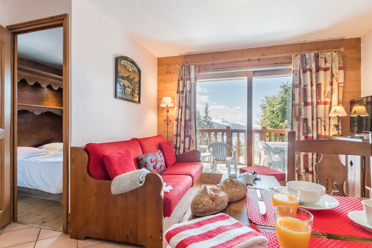 A living room with a red couch and a glass of orange juice