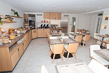 A dining room with tables and chairs and a counter full of food
