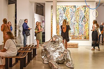 A group of people are looking at a painting in a museum
