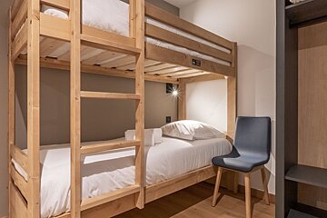 A bunk bed in a room with a chair