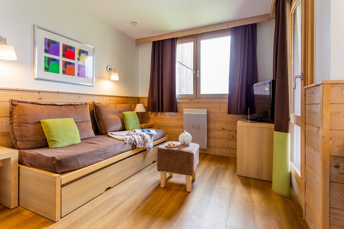A living room with a brown couch and green pillows