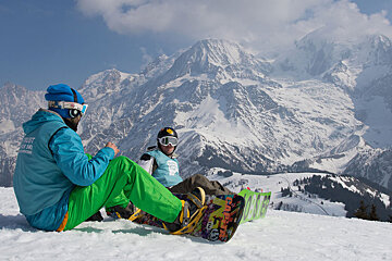 2 snowboarders sitting on a ski slope