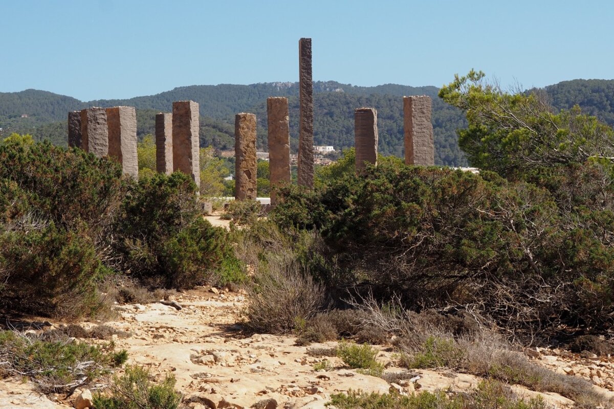 a view through the bushes to a stone art installation