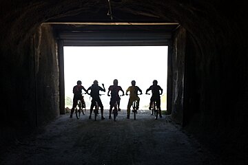 five mountain bikers silhouetted in a tunnel