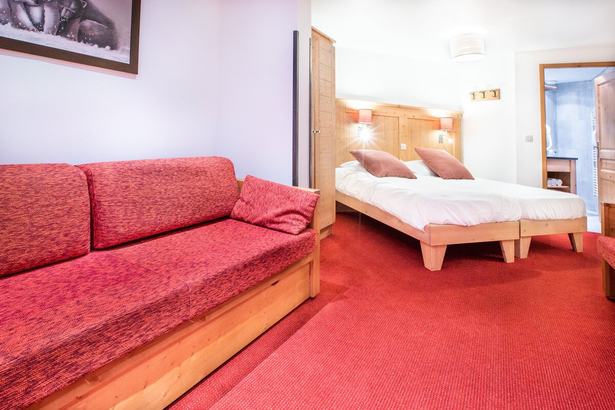 A hotel room with two beds and a red couch