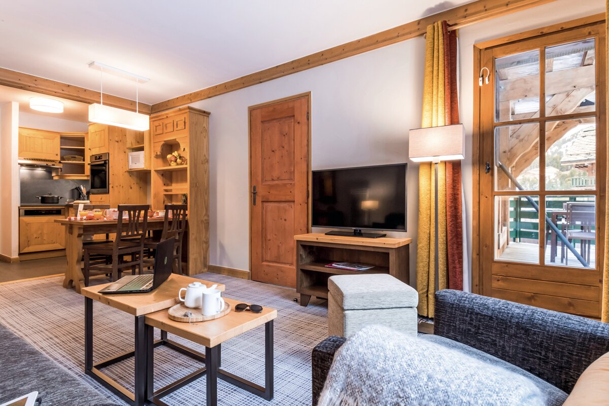 A living room with a table and chairs and a flat screen tv