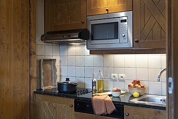 A kitchen with a microwave and a bottle of olive oil