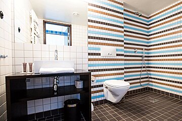A bathroom with striped tiles and a toilet