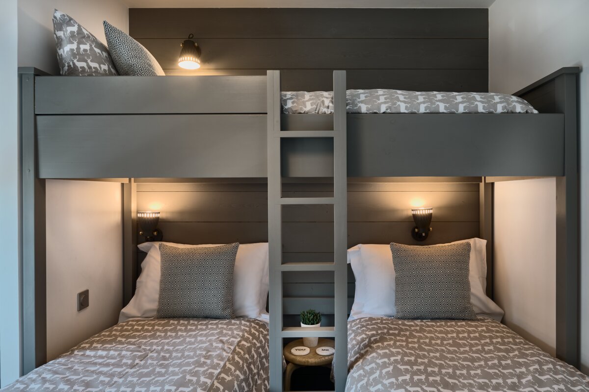 A bunk bed with a ladder between two twin beds