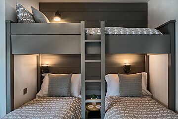 A bunk bed with a ladder between two twin beds