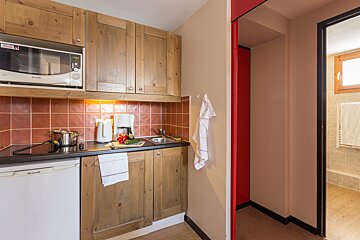 A small kitchen with a brandt dishwasher and a microwave