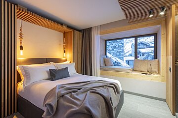 A bedroom with a bed and a window seat