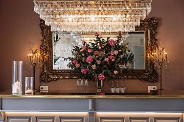 A bar with a large mirror and a vase of flowers on it