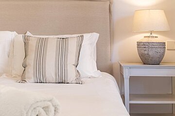 A striped pillow sits on a bed next to a lamp