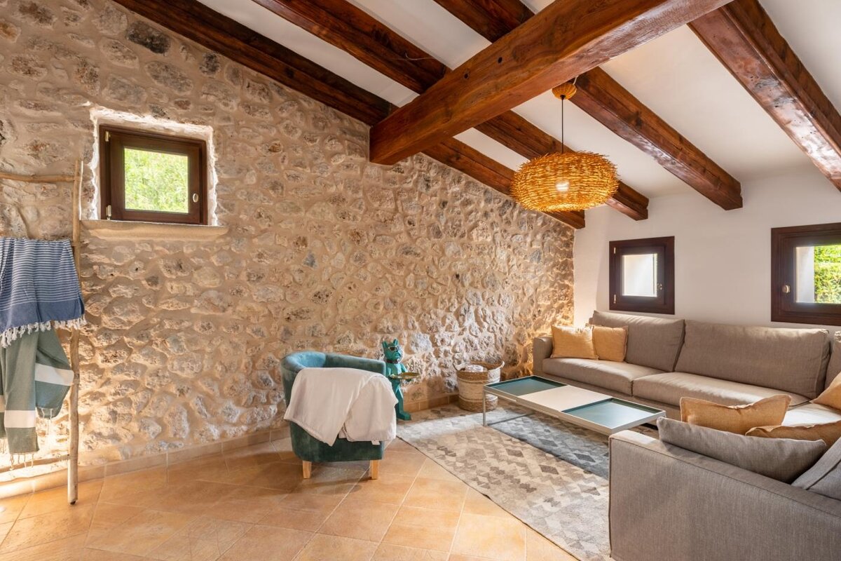 A living room with a stone wall and wooden beams
