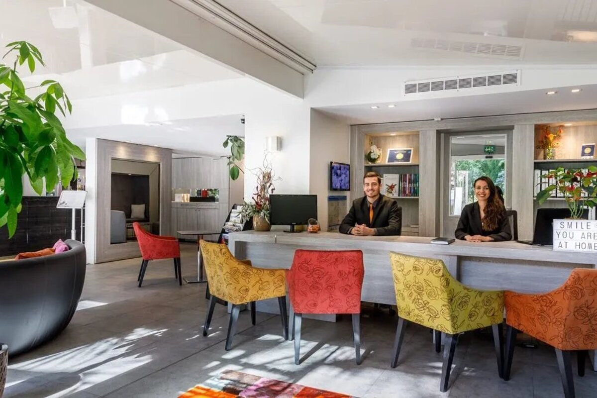 Two people sitting at a desk with a sign that says smile you are at home