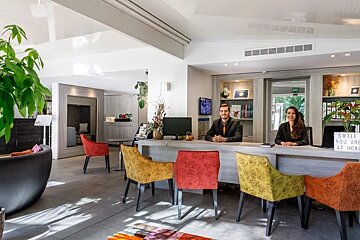 Two people sitting at a desk with a sign that says smile you are at home
