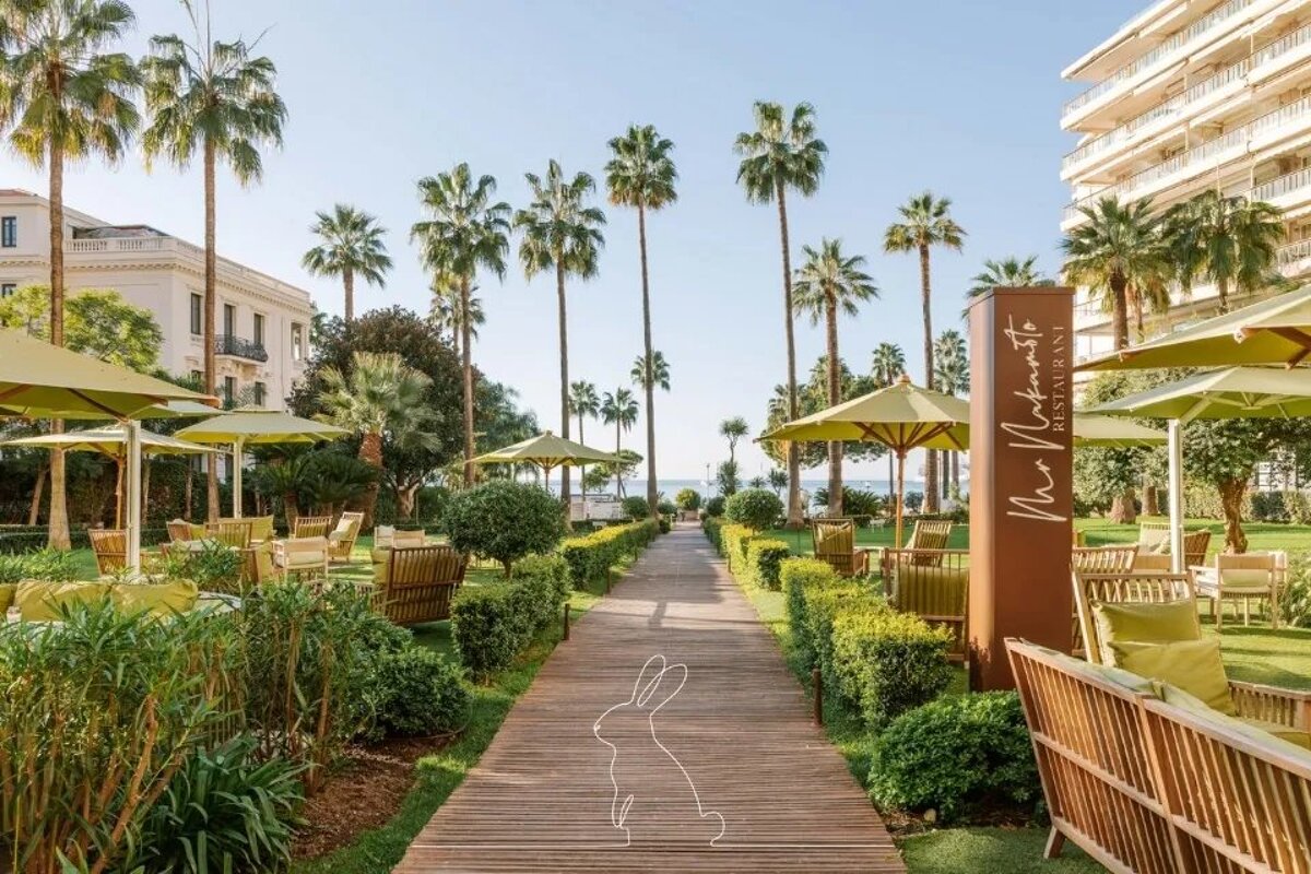 A wooden walkway leading to a restaurant with umbrellas and chairs