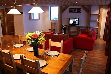 A dining table with plates and glasses and a vase of flowers on it