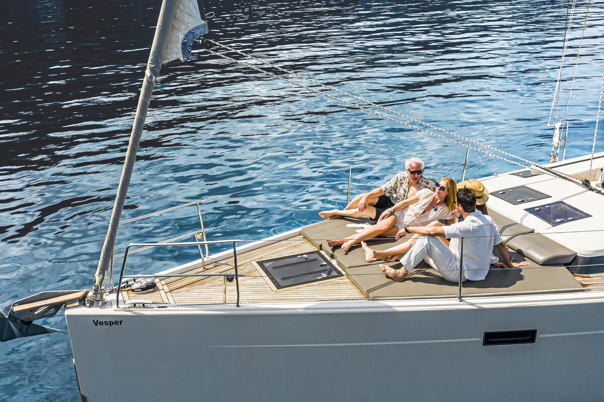A group of people sitting on the deck of a vesper sailboat