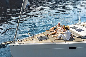 A group of people sitting on the deck of a vesper sailboat