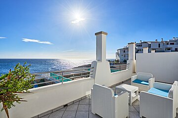 A balcony with chairs and a table overlooking the ocean