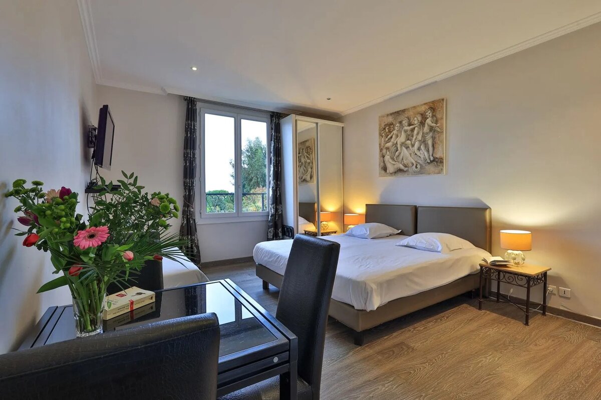 A hotel room with two beds and a vase of flowers on the table