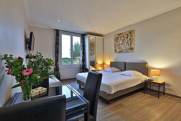 A hotel room with two beds and a vase of flowers on the table