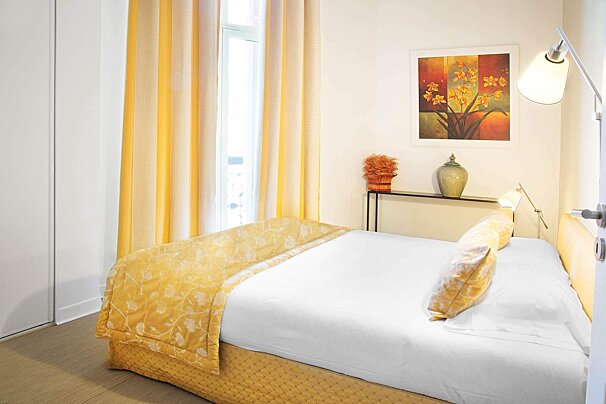 A bedroom with a picture of flowers on the wall above the bed