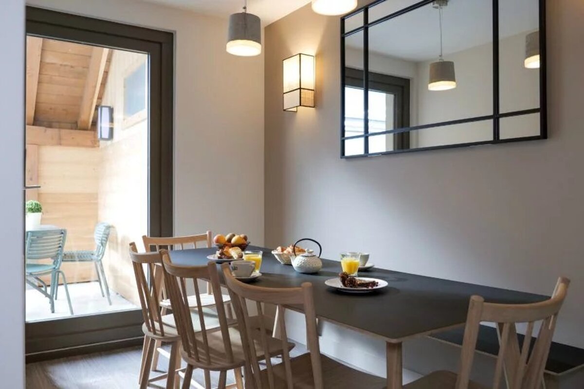A dining room with a table and chairs and a mirror