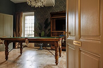 A pool table in a room with a sign that says billiard room