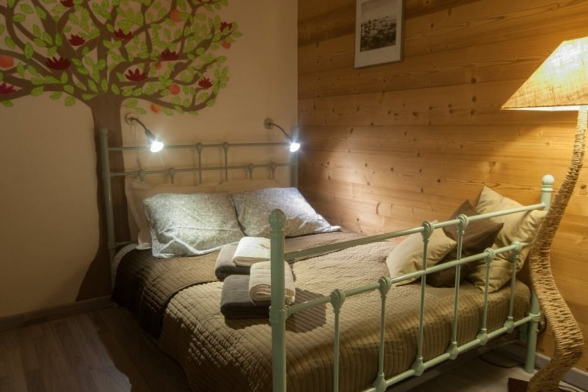 A bedroom with a tree painted on the wall above the bed