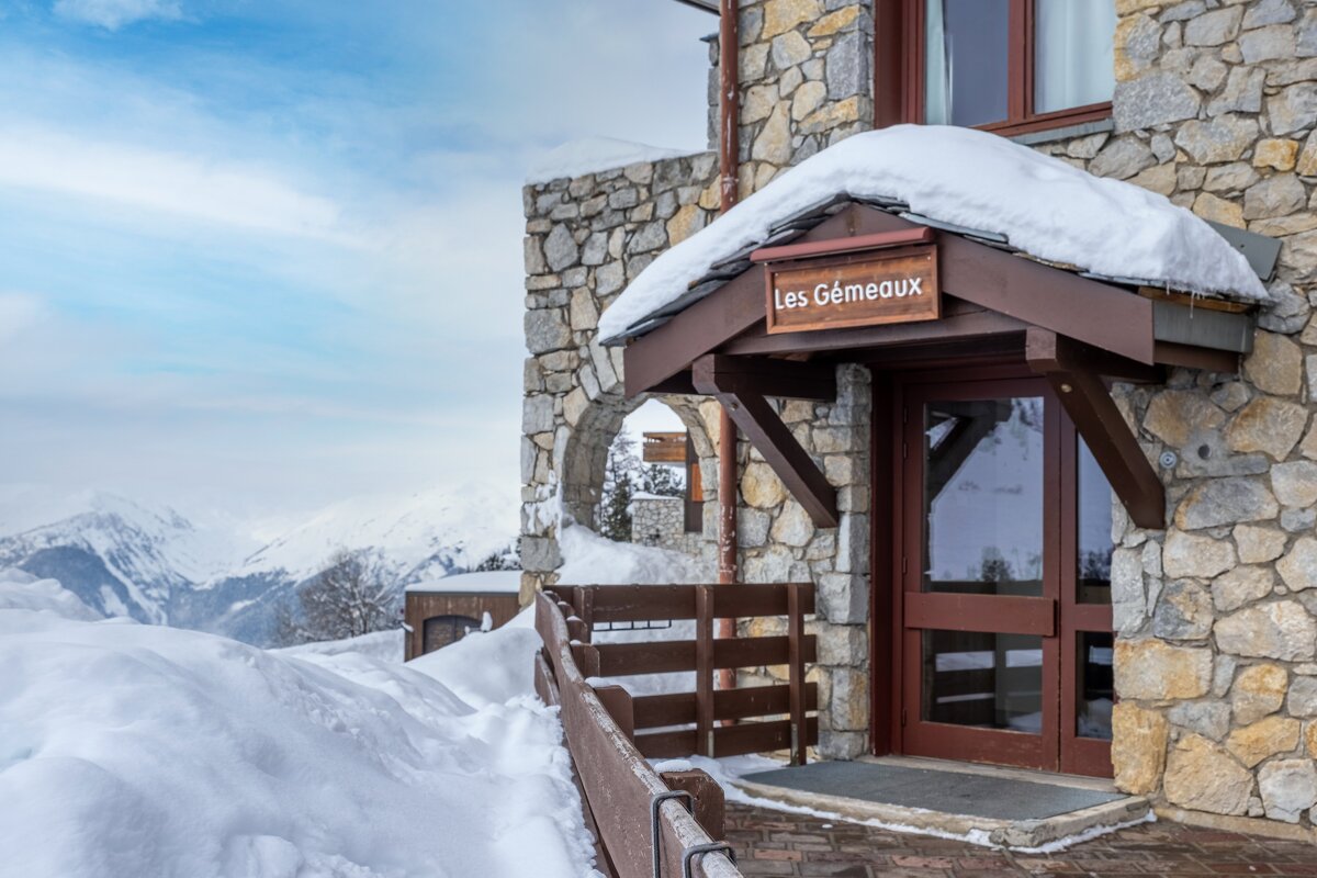 A stone building with a sign that says les gemeaux on it