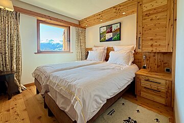 A bedroom with two beds and a painting on the wall