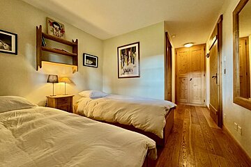 A bedroom with two beds and a painting on the wall that says valais