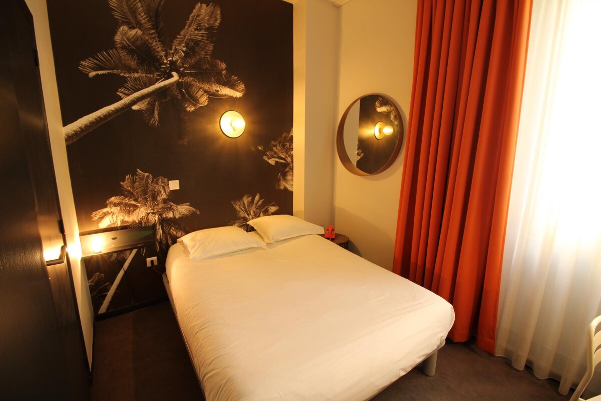 A hotel room with a bed and a mirror