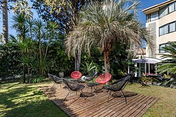 A wooden deck with chairs and a table under a palm tree