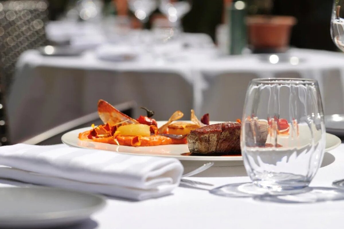 A glass of water sits on a table next to a plate of food