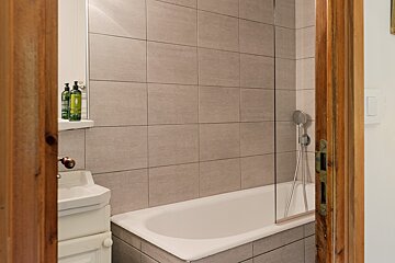 A bathroom with a bathtub and two bottles of lotion on a shelf