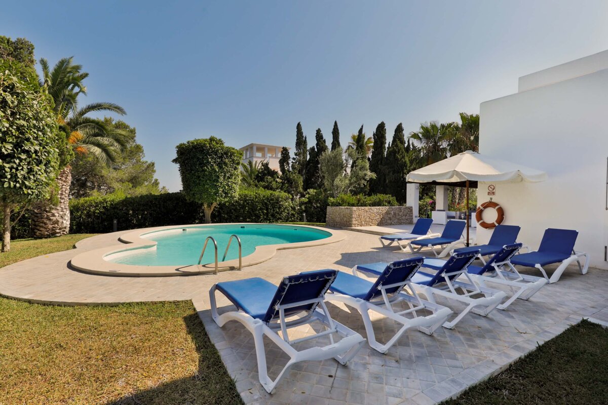A swimming pool is surrounded by blue chairs and a white umbrella