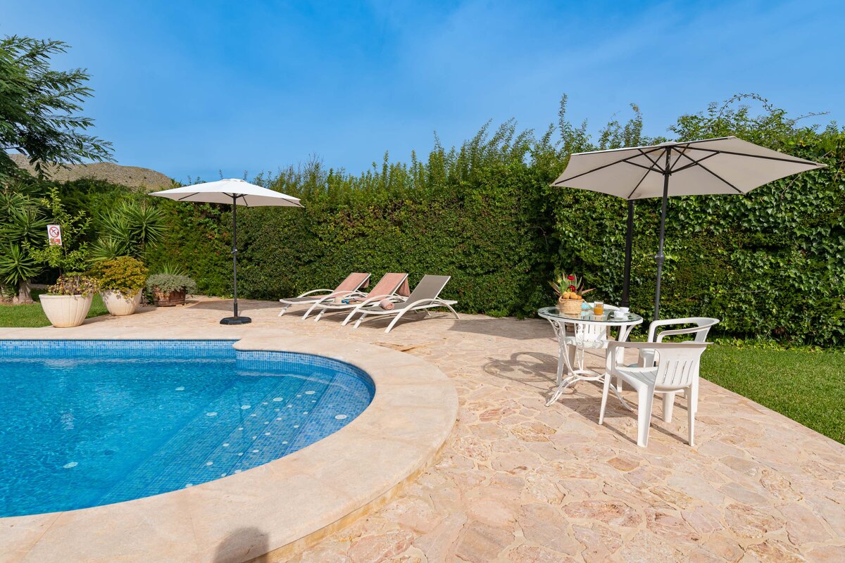 A swimming pool with a table and chairs and an umbrella